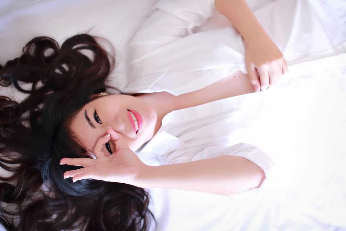 white shirt happy women lying on bed
